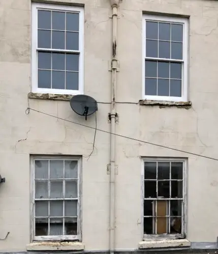 Two new traditional sliding sash windows installed above.
Traditional lead weight and putty glazed heritage units.
Made to specifications to match the listing requirements. 
Finished in exterior top coat. image