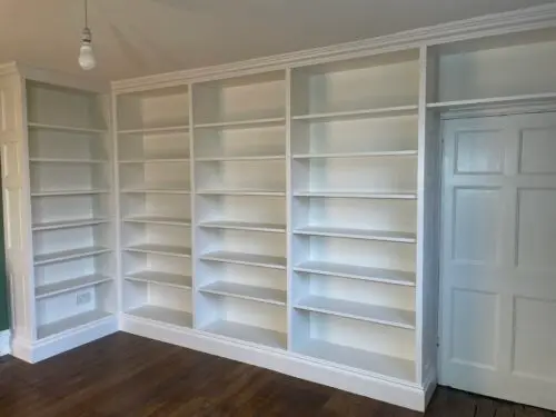 Fitted Bookcase with traditional cornice and skirting board.
Fixed shelves with a traditional face frame. 
Spray finished in Colour match topcoat (F&B Pointing)
Panelling to match the existing door design image